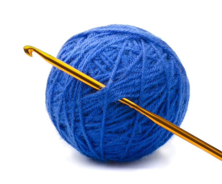Ball of blue yarn and crochet hook isolated on white
