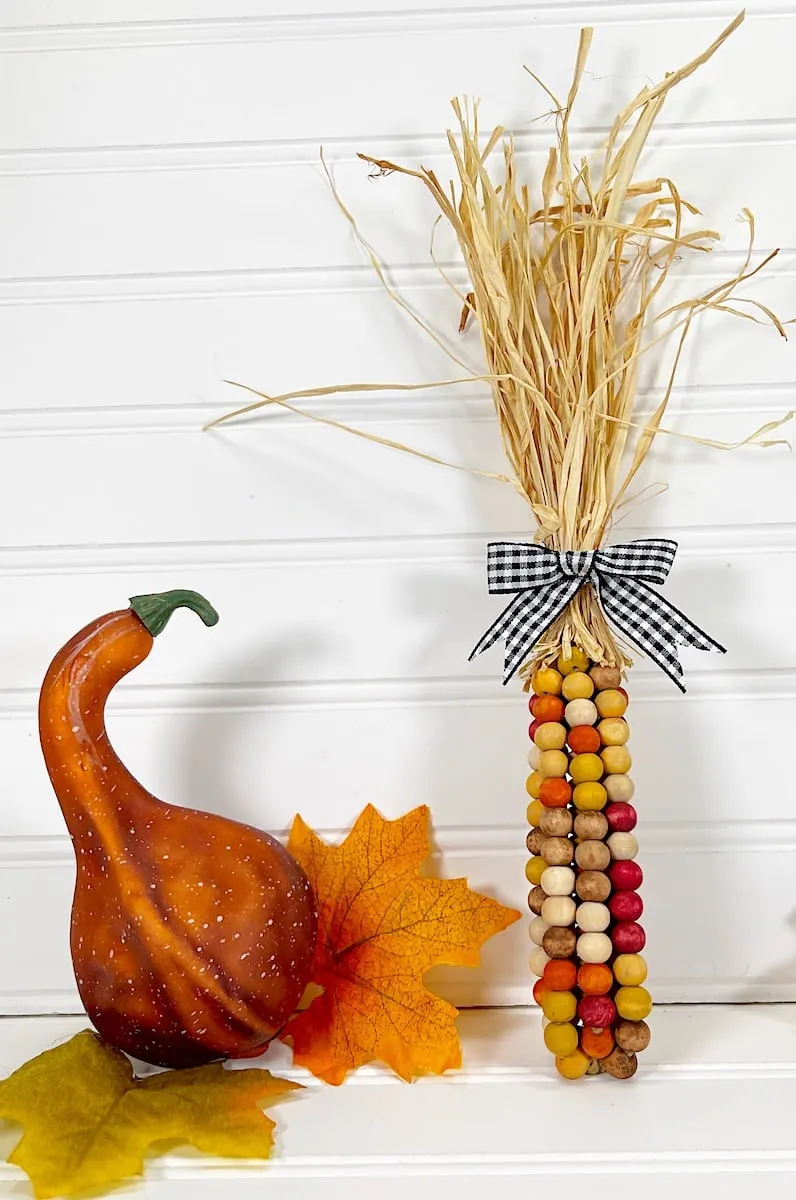Bead Corn with orange fall leaves and a gourd on a white background