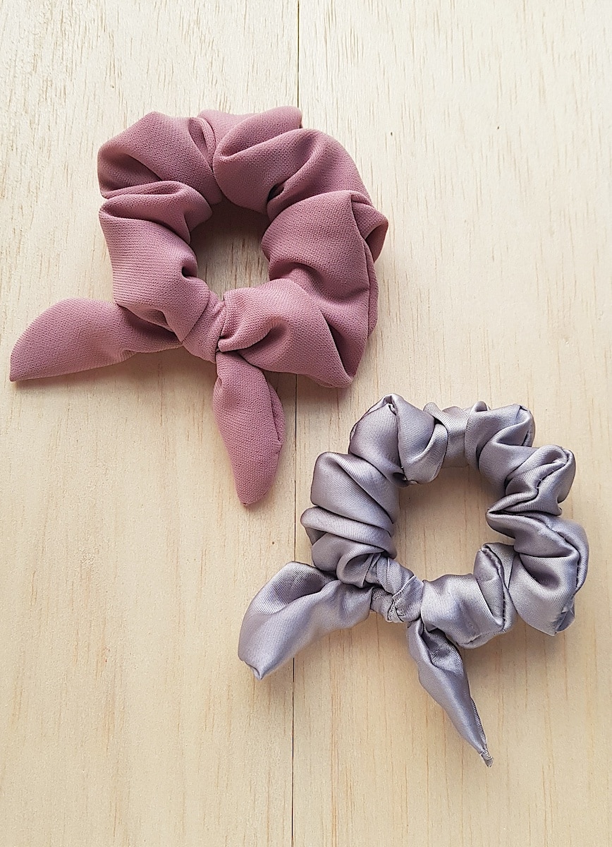 Bow Scrunchie Two pink and grey scrunchies on a wooden surface.