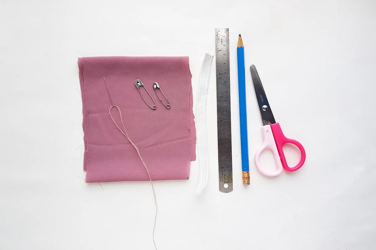 Bow Scrunchie Supplies A pair of scissors and a piece of fabric are laid out on a white surface.