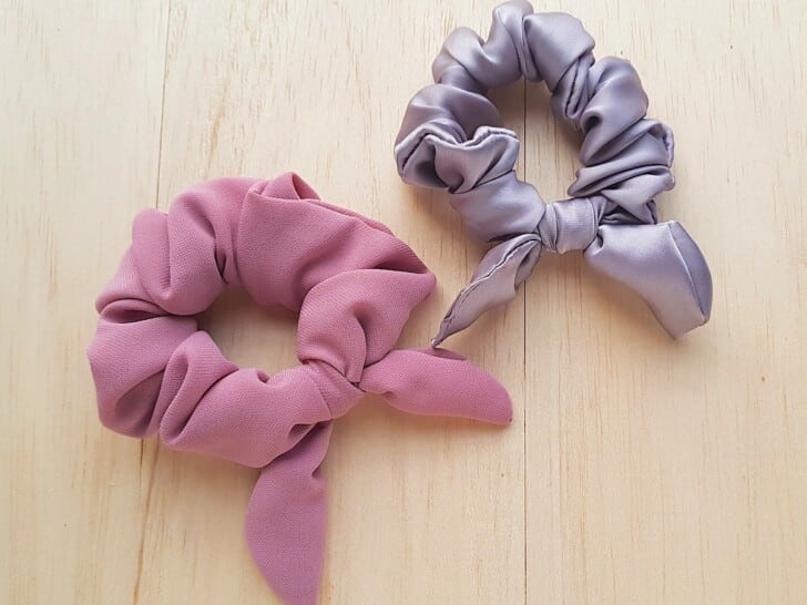 Bow Scrunchie Two pink and grey scrunchies on a wooden surface.