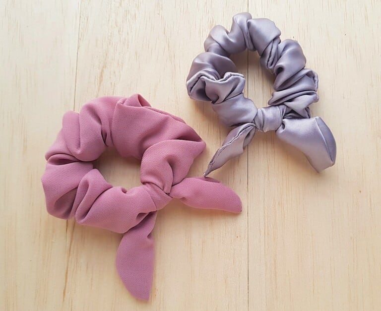 Bow Scrunchie Two pink and grey scrunchies on a wooden surface.