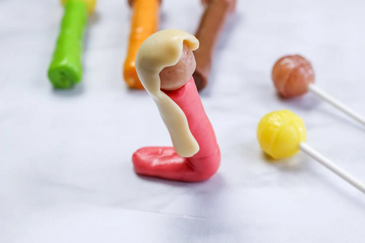 Candy Nativity Step 10 forming hair with tootsie rolls and lollipops.