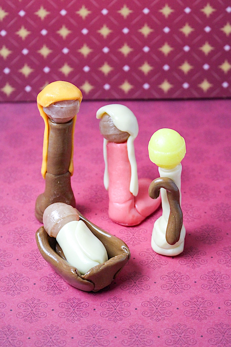 A group of candy figurines on a pink background.