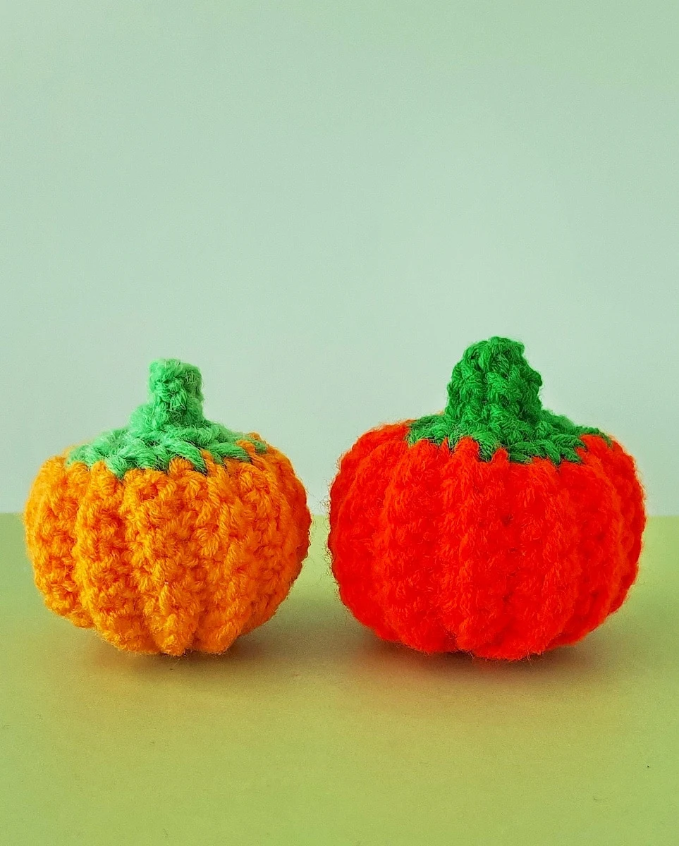 Two different colored Crochet Pumpkins on green background
