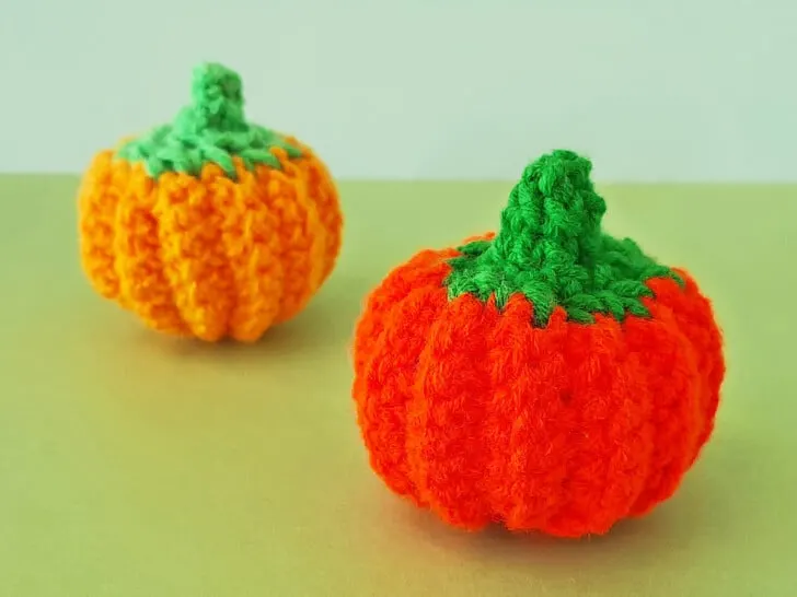 Crochet Pumpkins one light orange and a deep orange in color on green backdrop