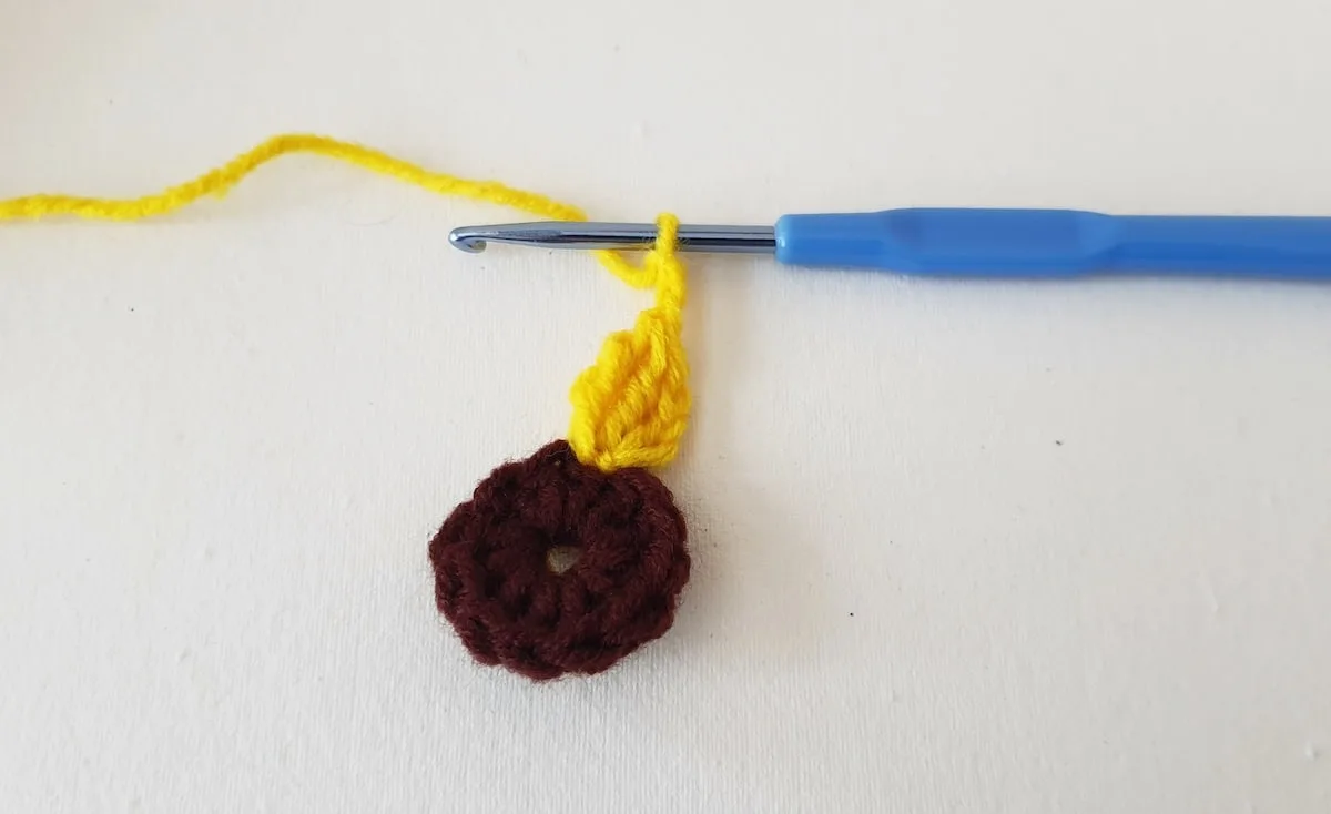 Crochet Sunflower Granny Square Step 12 A crocheted donut on a white surface.