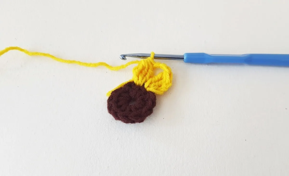 Crochet Sunflower Granny Square Step 14 A crocheted acorn with a yellow and brown yarn.