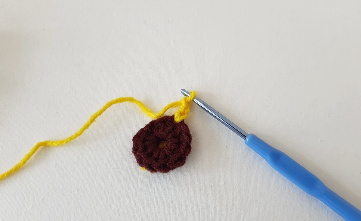 Crochet Sunflower Granny Square Step 8 A crocheted flower with a needle and a crochet hook.
