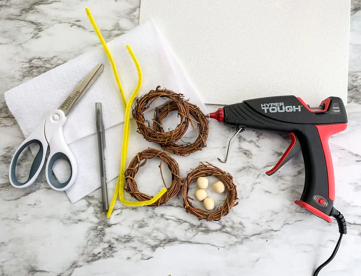 Emmanuel Wreath materials A glue gun, scissors, and glue on a marble table.