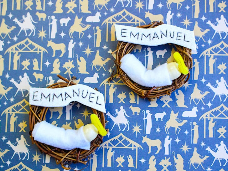 two Emmanuel Wreath ornaments with baby Jesus figures on a blue background with Biblical figures
