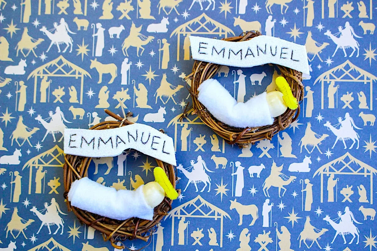 Emmanuel Wreath with two nativity ornaments on a blue background with Biblical figures