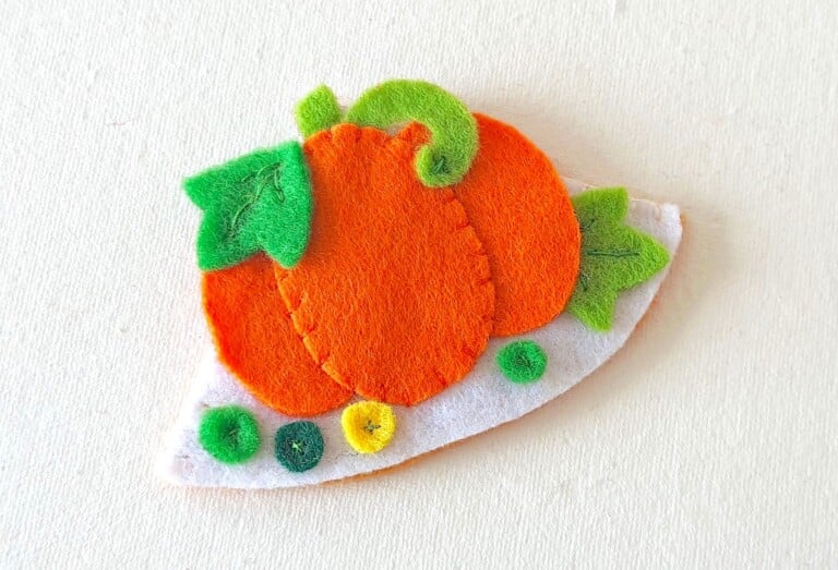 Fall Bookmark Craft felt green leaves atop orange pumpkin on solid white background