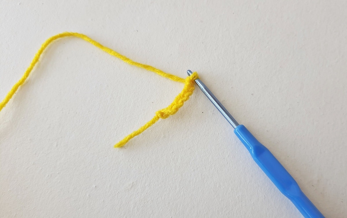 Maple Leaf Crochet Pattern Step 1 A yellow crochet thread with a blue crochet hook.