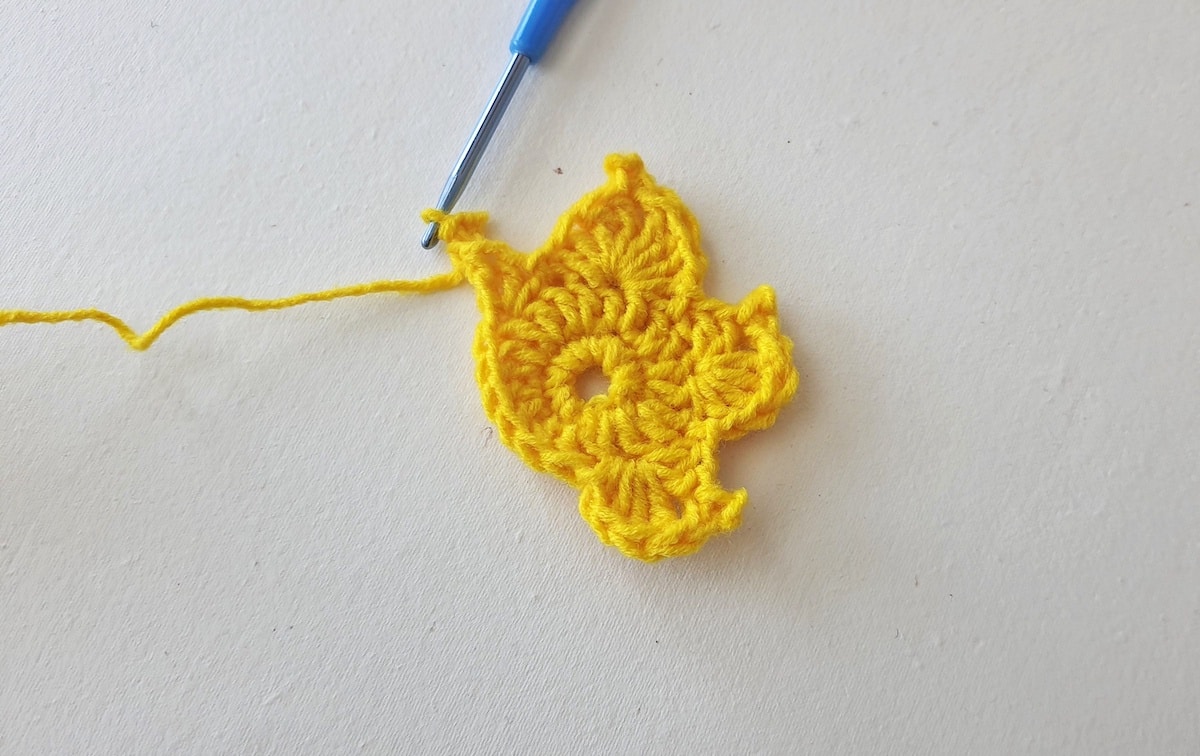 Maple Leaf Crochet Pattern Step 15 A yellow crocheted flower with a blue needle.