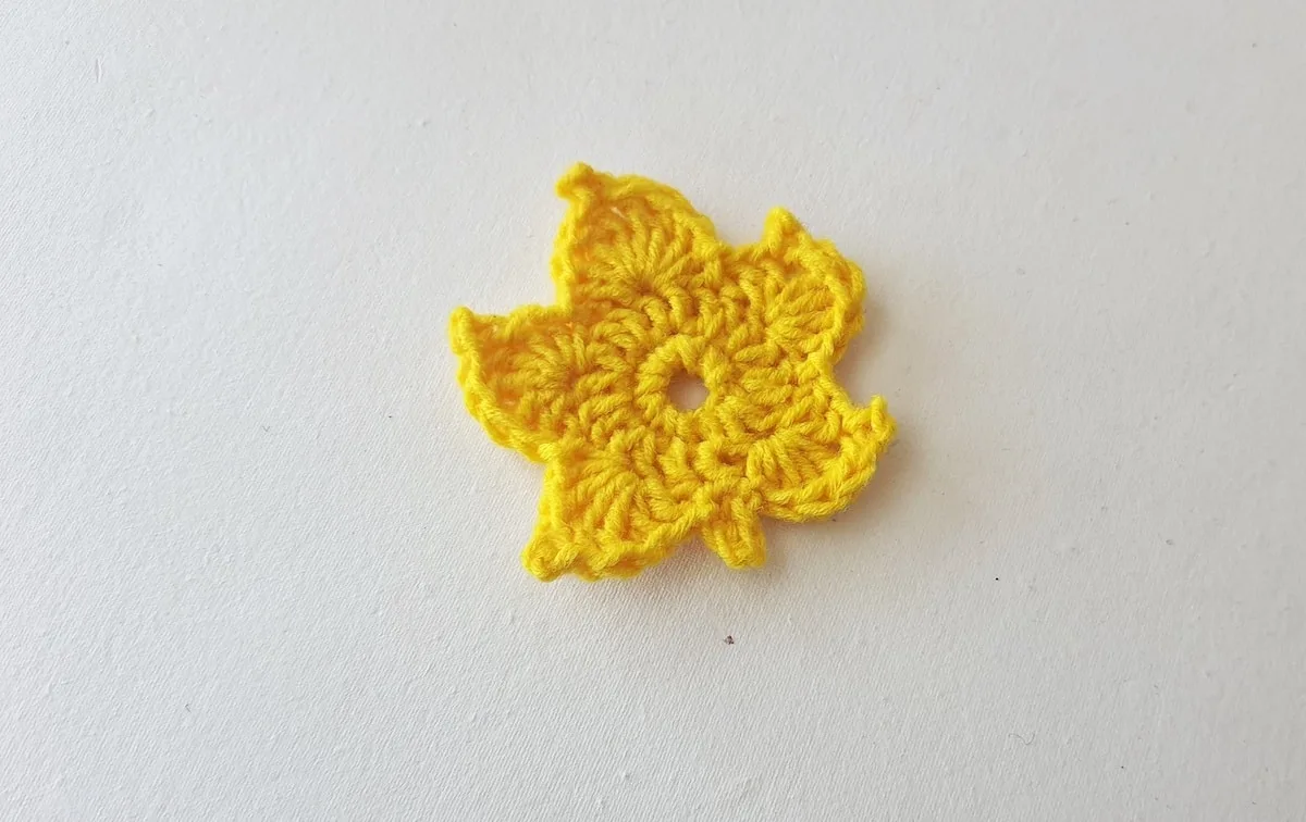 Maple Leaf Crochet Pattern Step 21 A yellow crocheted leaf on a white surface.
