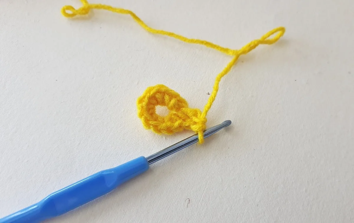 Maple Leaf Crochet Pattern Step 4 A yellow crochet hook is being used to make a crocheted flower.