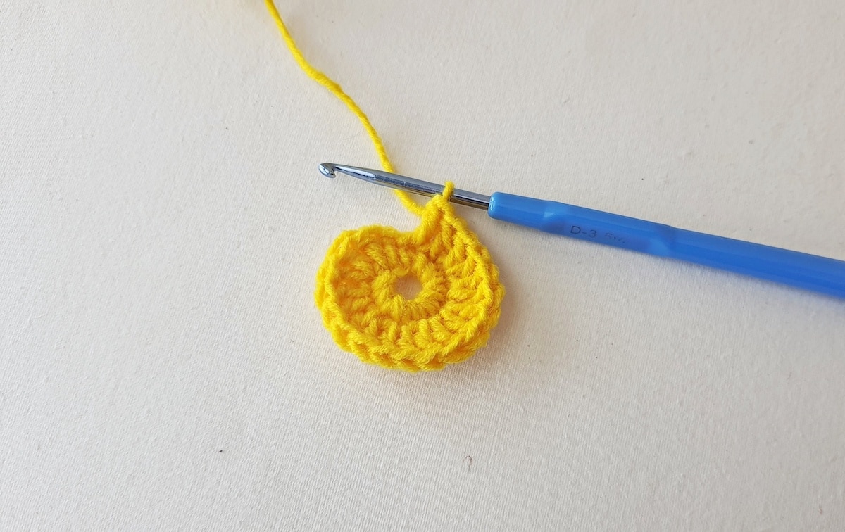 Maple Leaf Crochet Pattern Step 5 A yellow crocheted flower with a blue crochet hook.