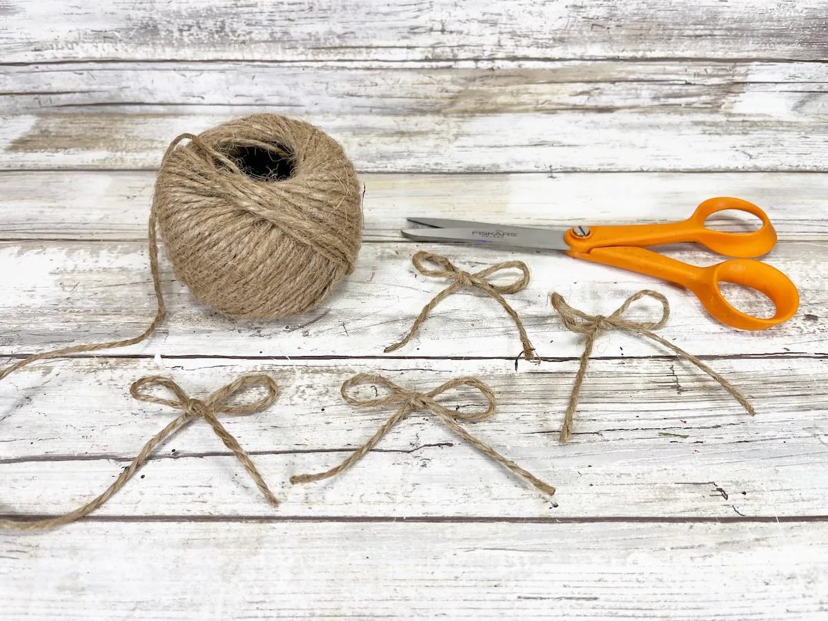 Candy Apple Craft Step 8A pair of scissors and a ball of jute on a wooden table.