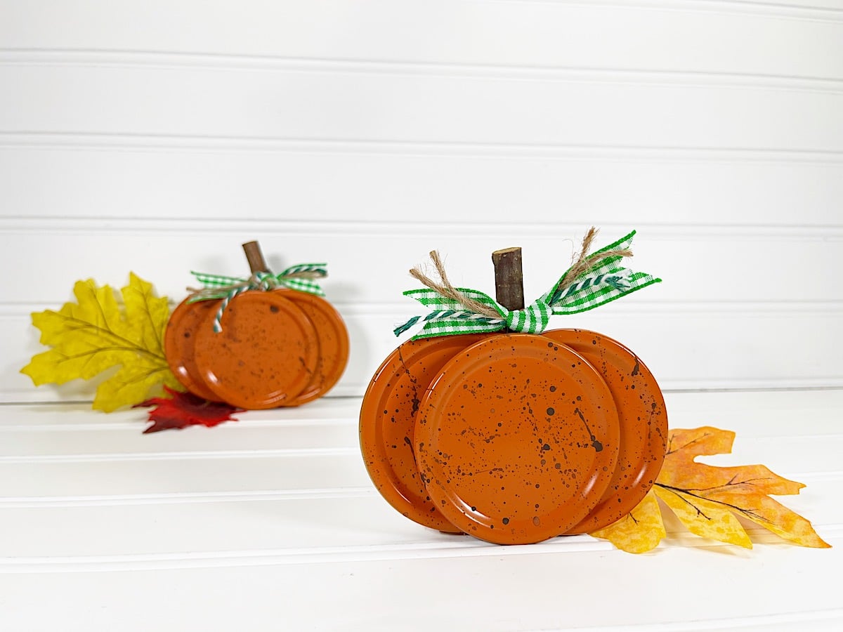 Canning Lid Pumpkins with green checkered ribbon atop against white background
