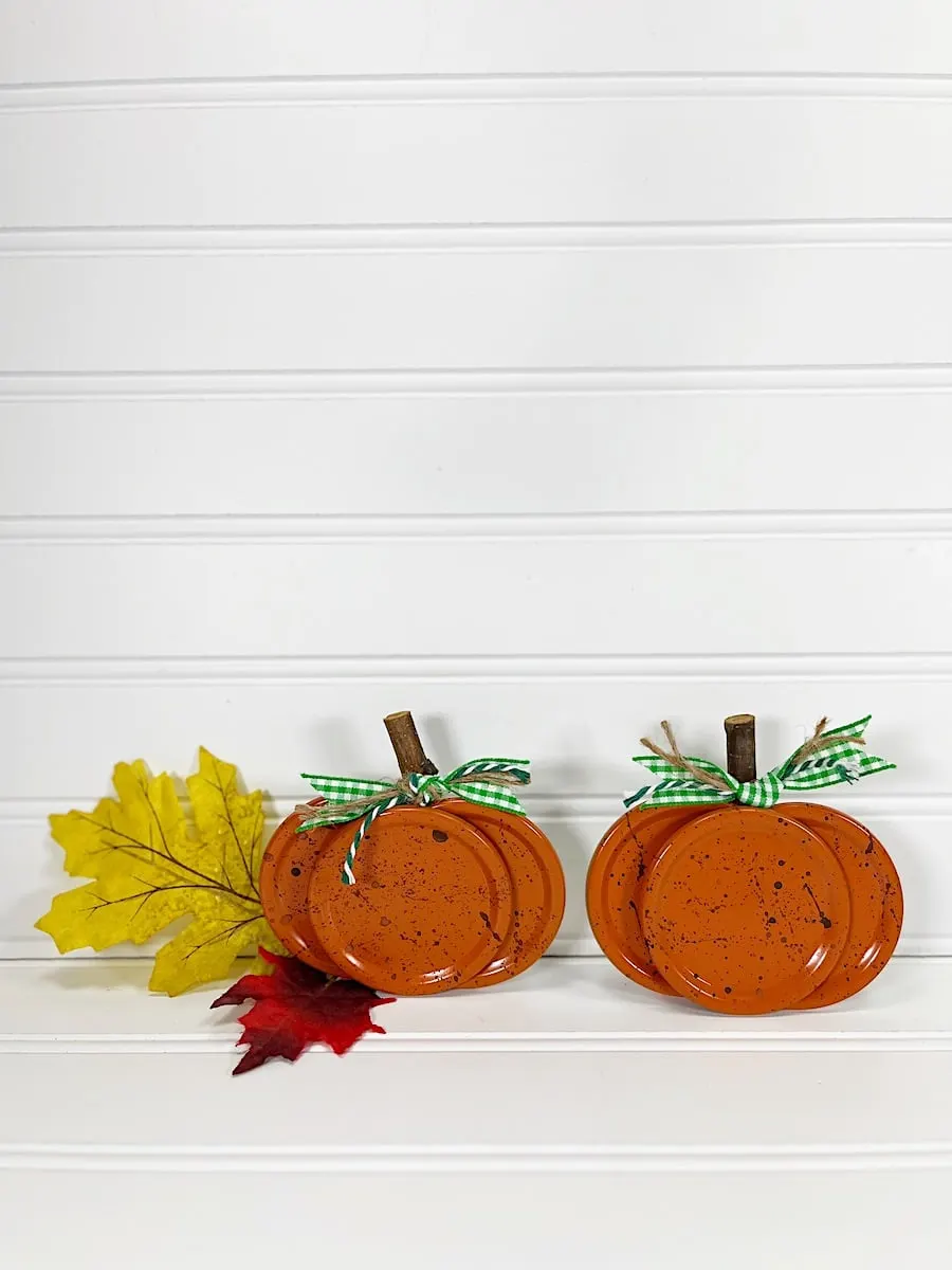 Canning Lid Pumpkins against a white wood background with fall leaves