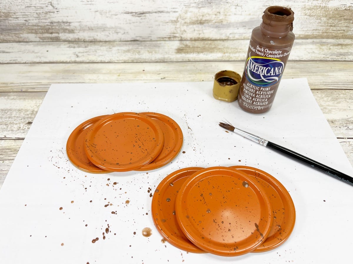 Canning Lid Pumpkins Step 4 on white background with brown paint and brush