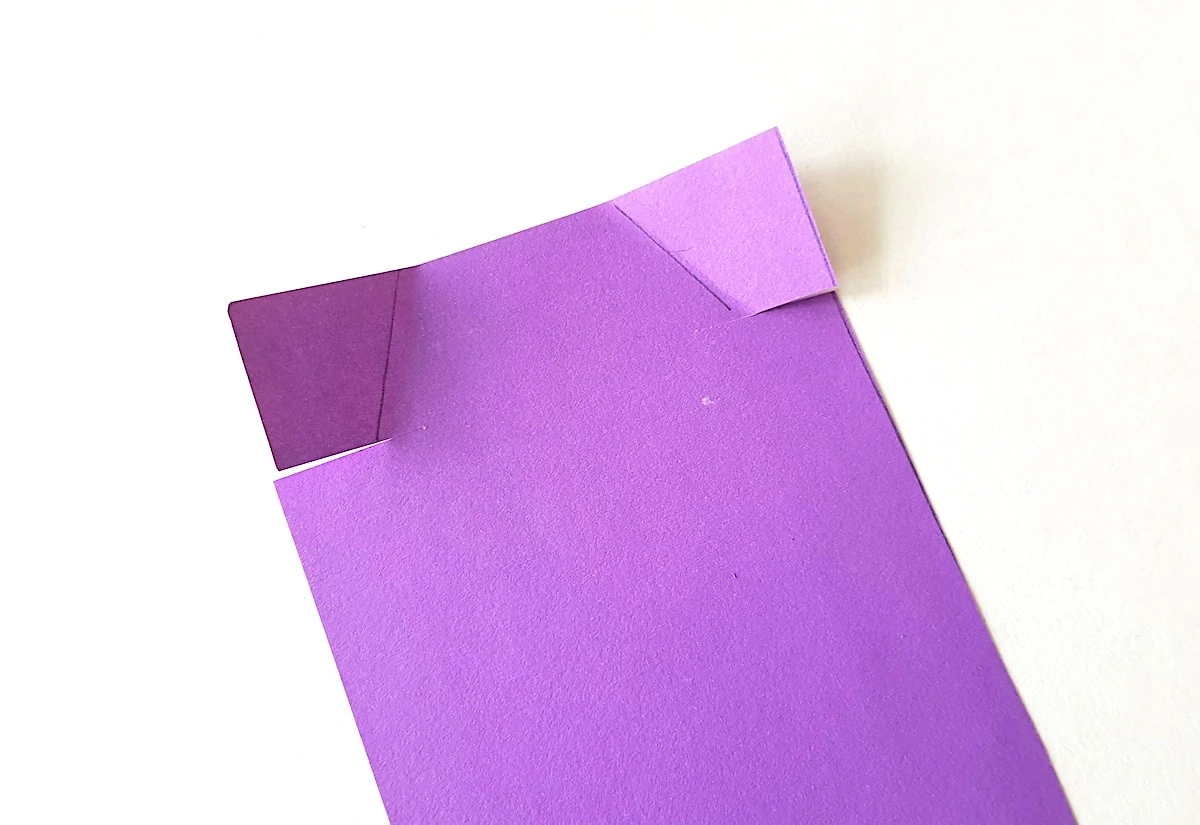 Doctor Apron Step 4 A piece of purple paper folded into a triangle.