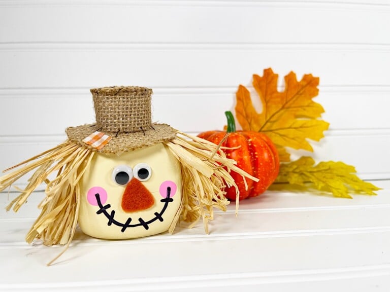 Foam Dice Scarecrow with a hat and leaves on a table.