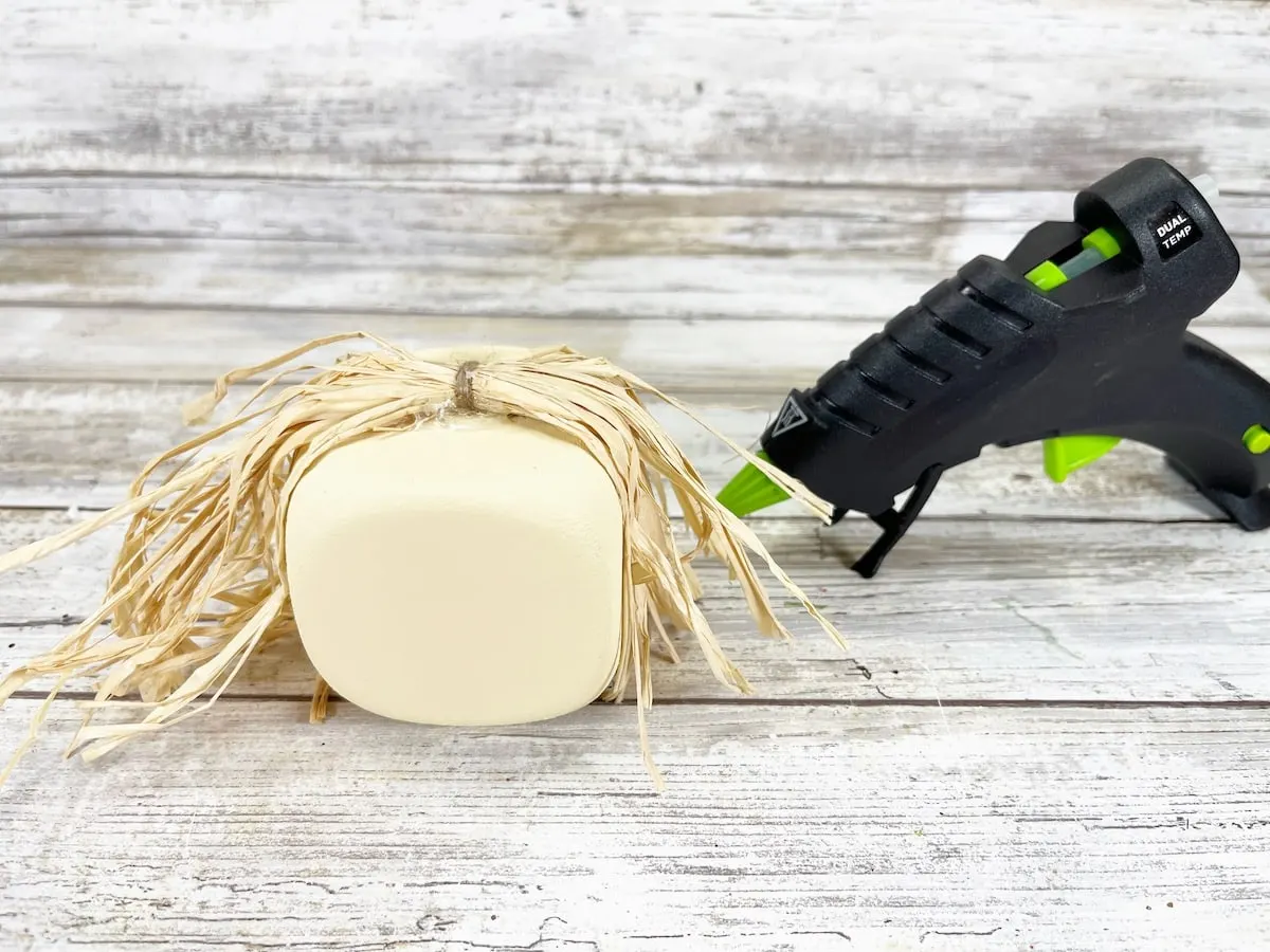 Foam Dice Scarecrow Step 4 glue gun next to a piece of hay.