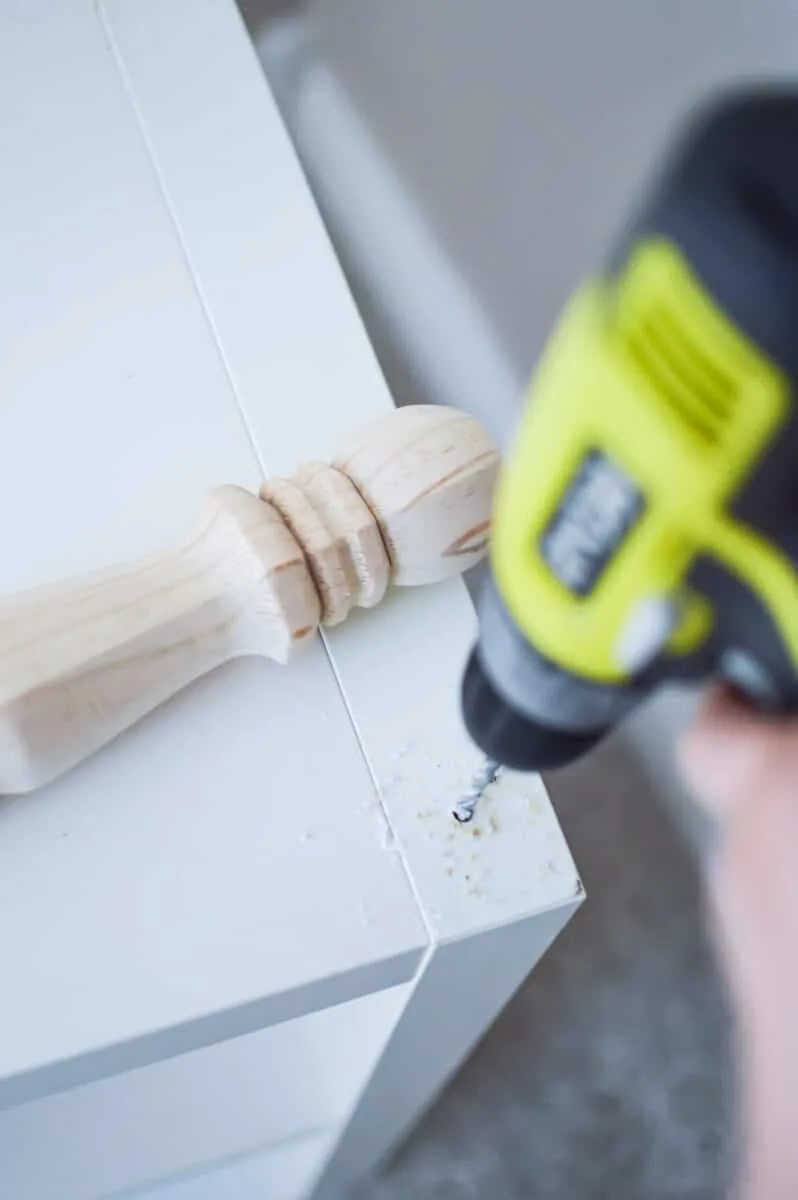 A person using a drill on a wooden table.