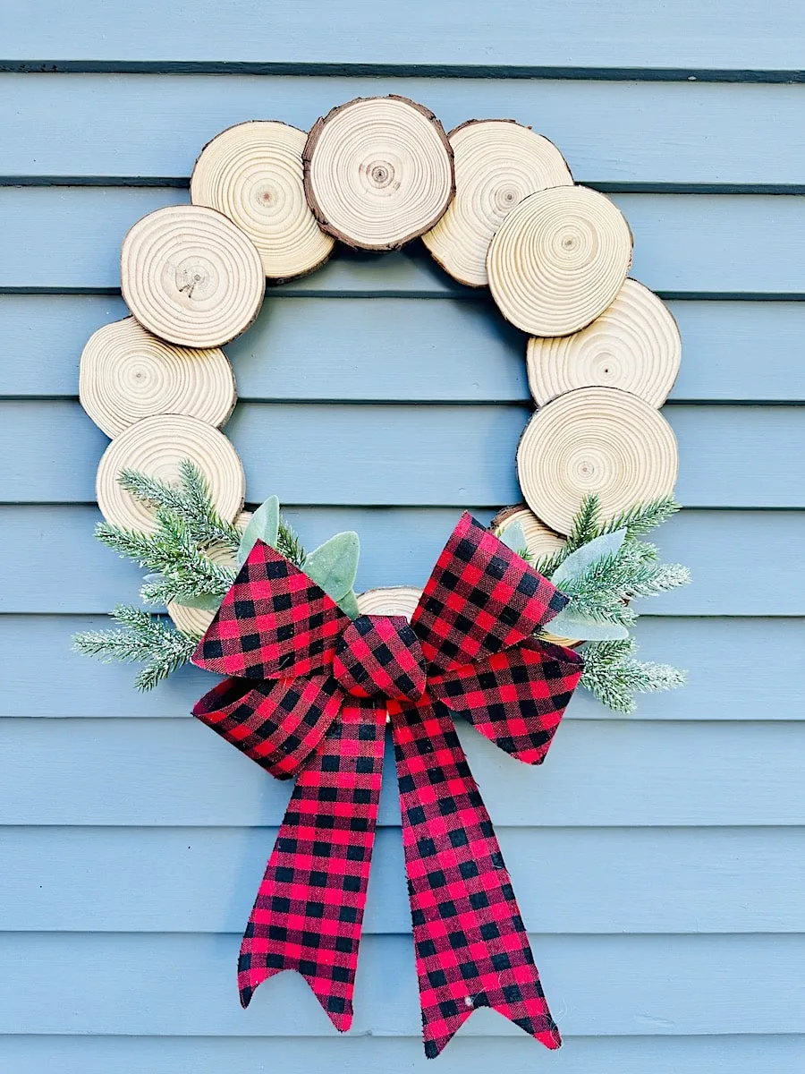 Wood Slice Wreath with red check bow against light blue background