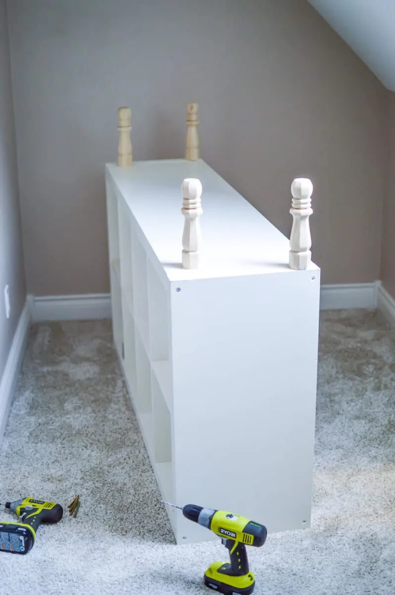 A white bookcase is being built in an attic room.