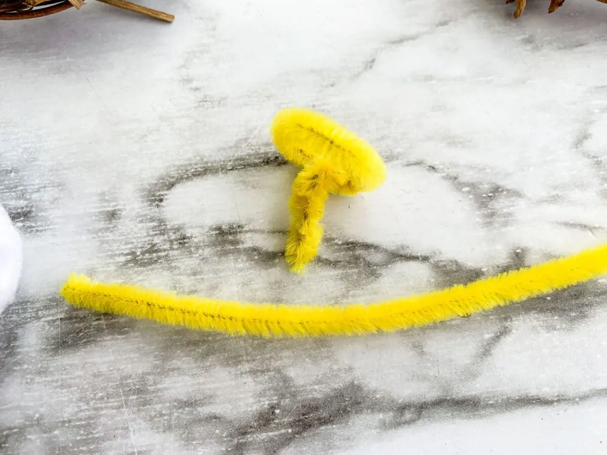 A bunch of yellow pom poms arranged on a marble table in the shape of Emmanuel Wreath.