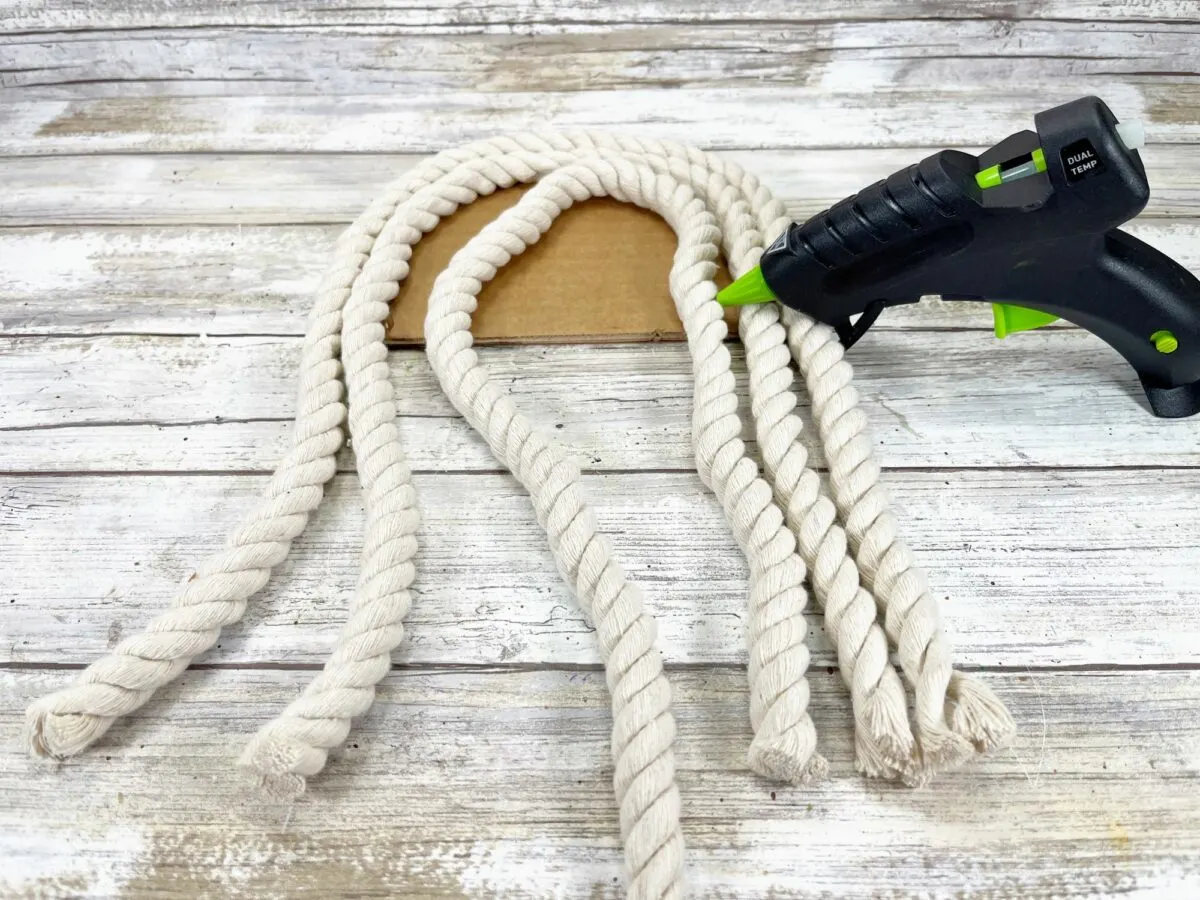 A white rope with a green glue gun on a wooden surface.