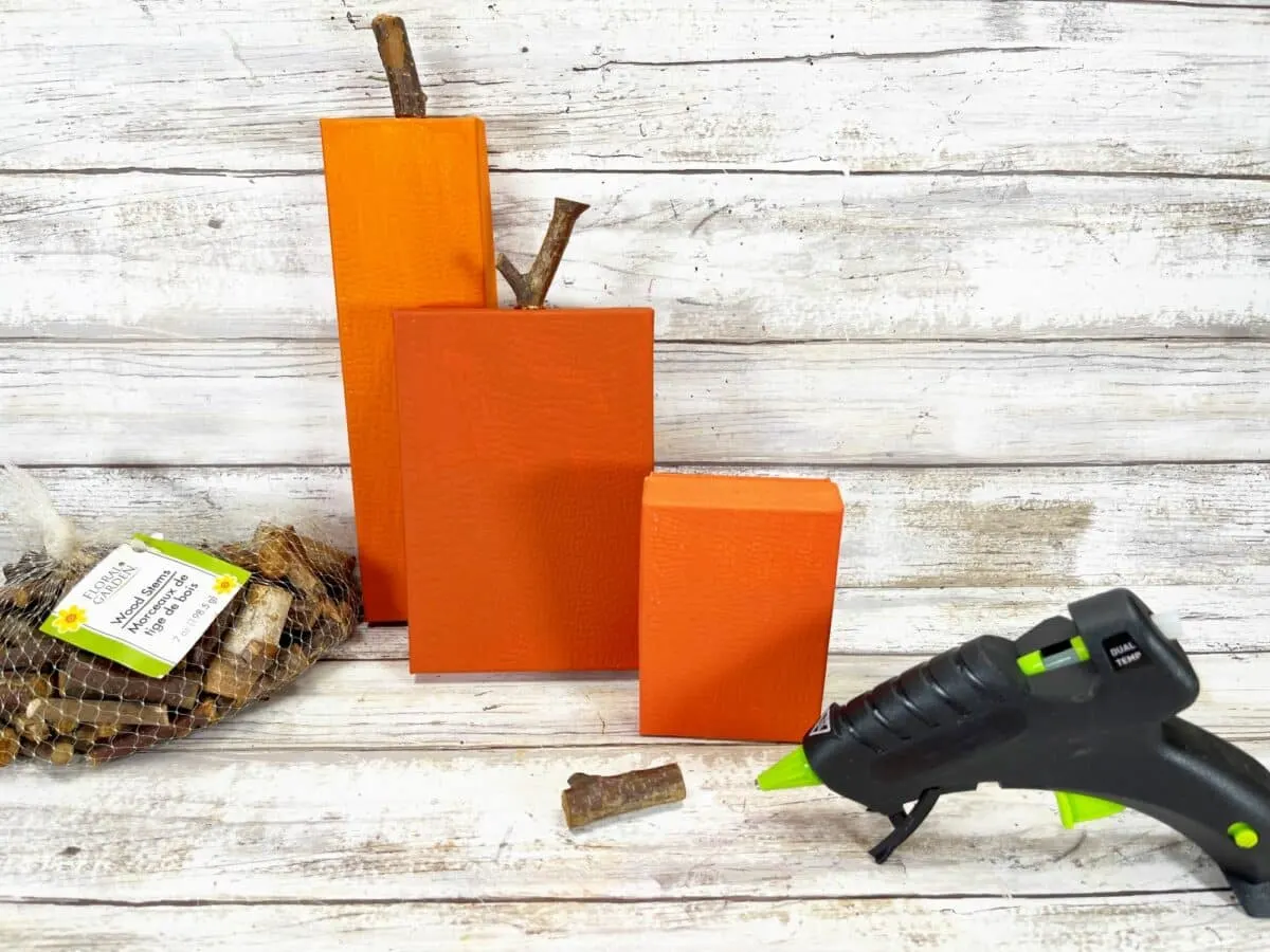 A group of orange pumpkins and a glue gun on a wooden table.