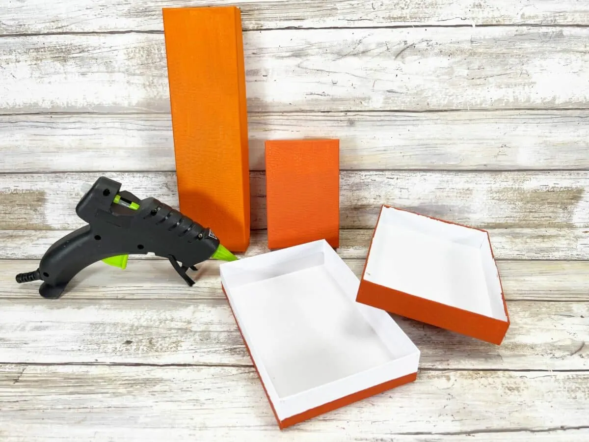 An orange box with a glue gun on top.