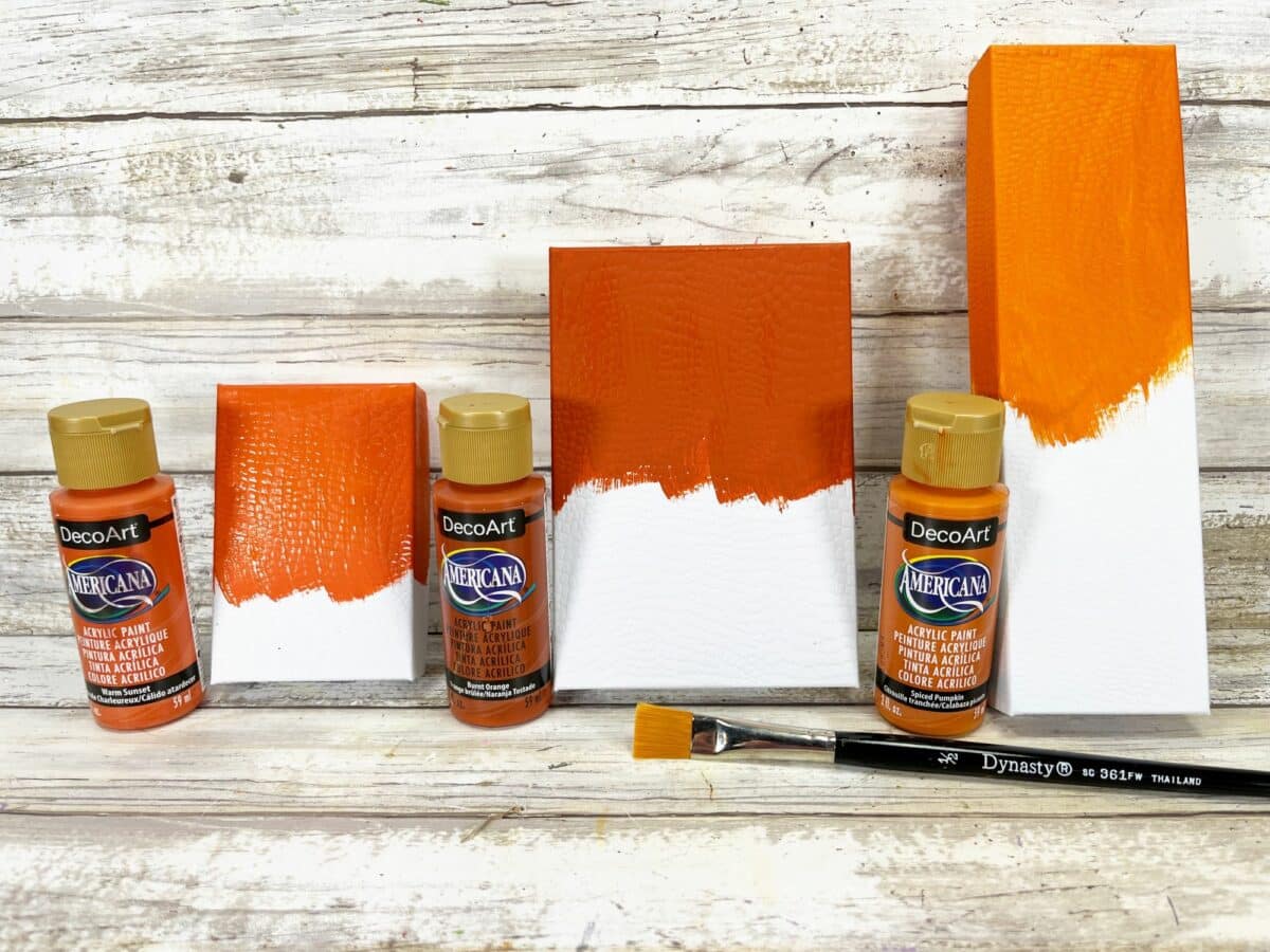 A set of orange paints and brushes on a wooden table.