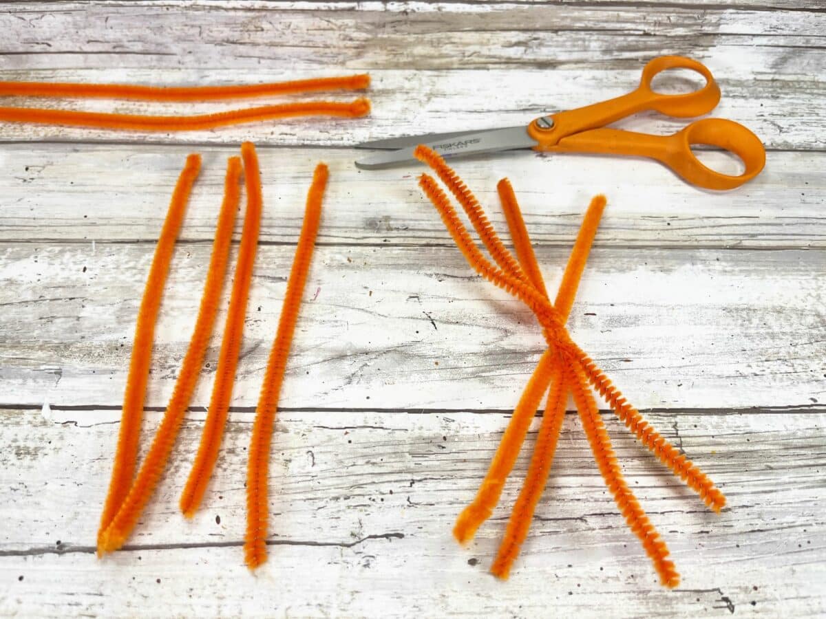 Orange craft sticks and scissors on a wooden table.