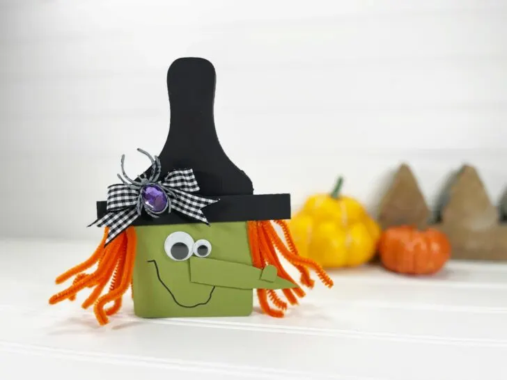 diy cutting board witch on a white table next to pumpkins.