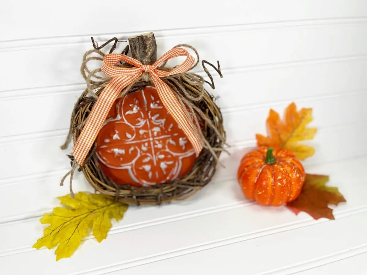 A pumpkin in a basket with leaves and a bow.