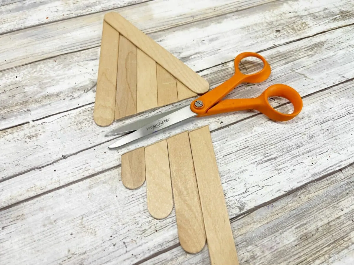 A pair of scissors next to a pair of popsicle sticks.