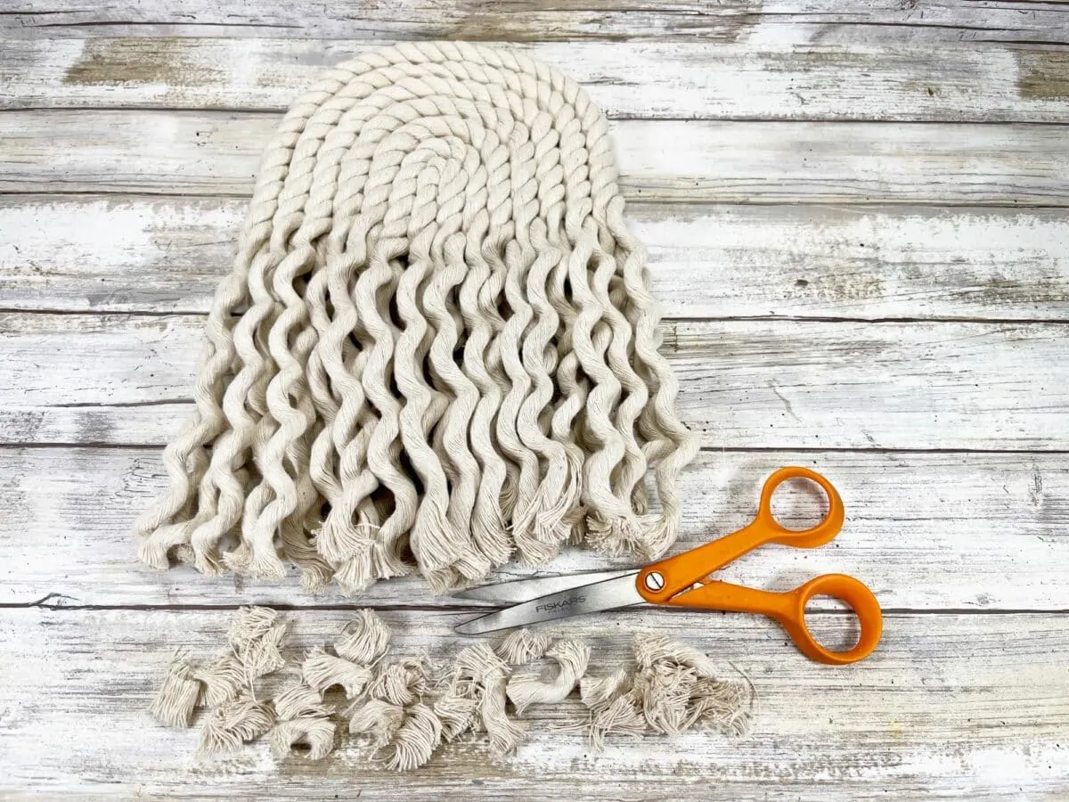 A crocheted hat and scissors on a wooden table.