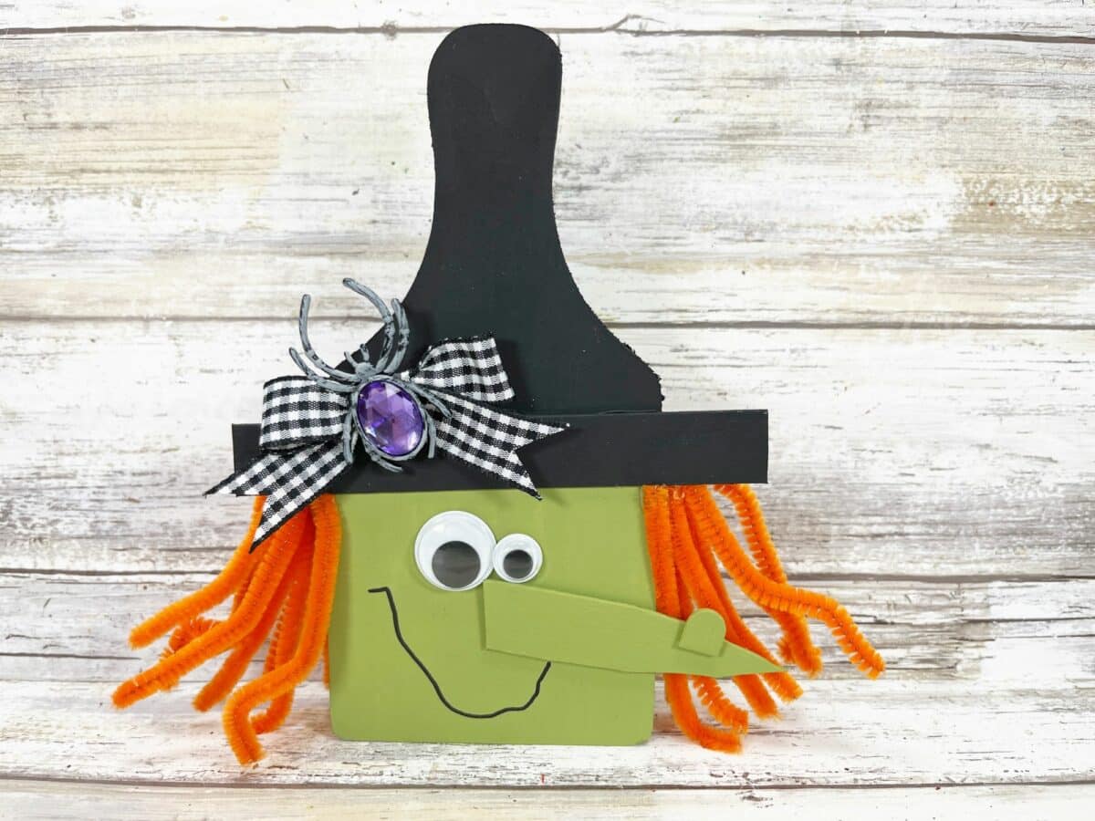 A witch with a green hat on a wooden background.