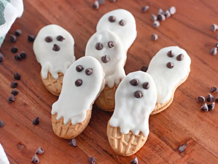 Ghost cookies on a wooden cutting board.