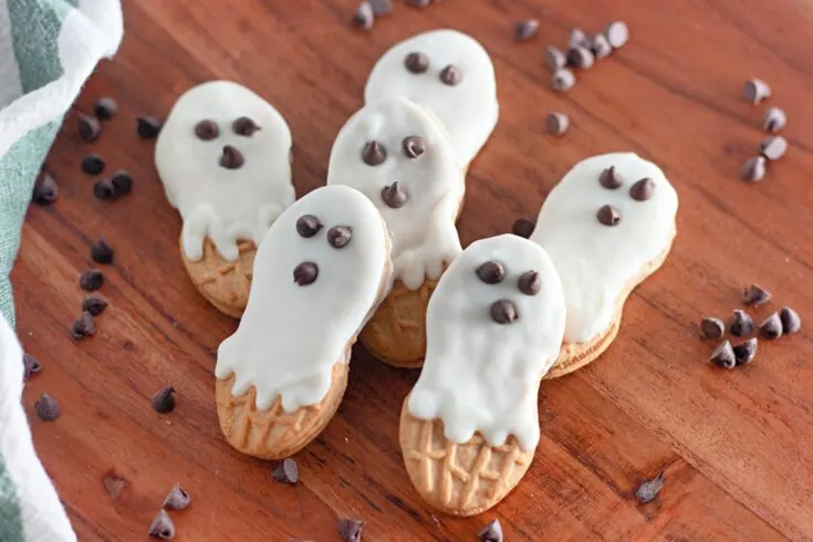 Ghost cookies on a wooden cutting board.