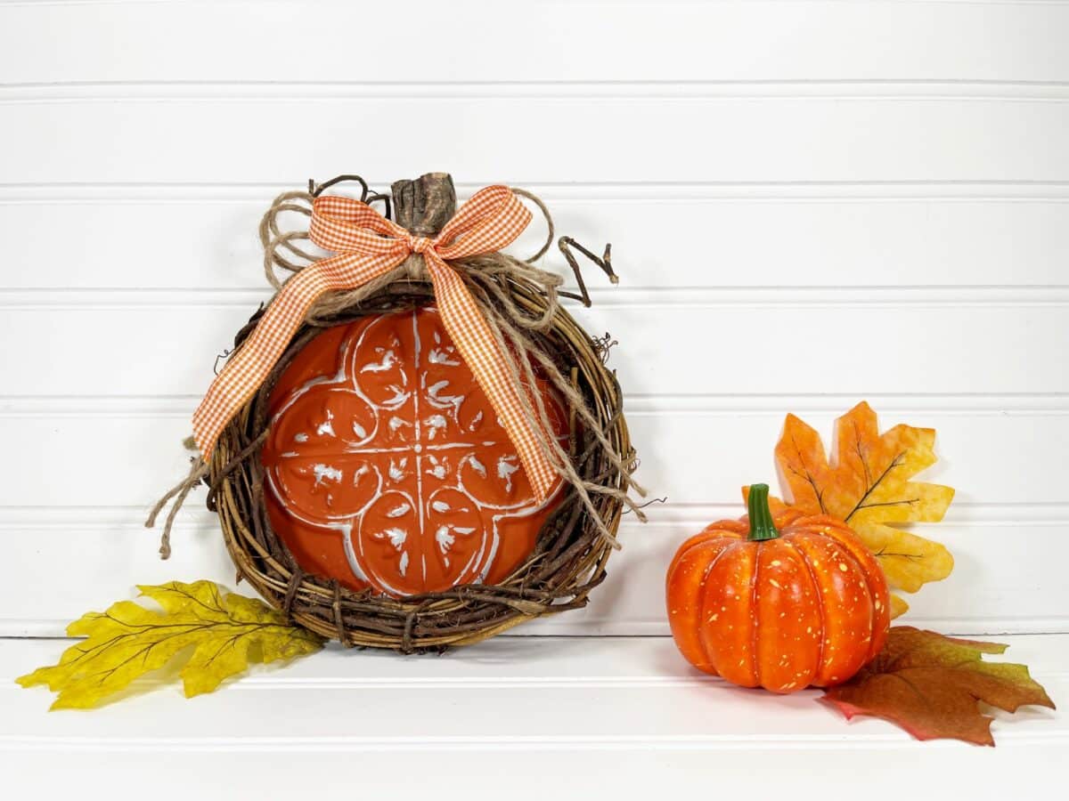A pumpkin in a basket with leaves and a bow.