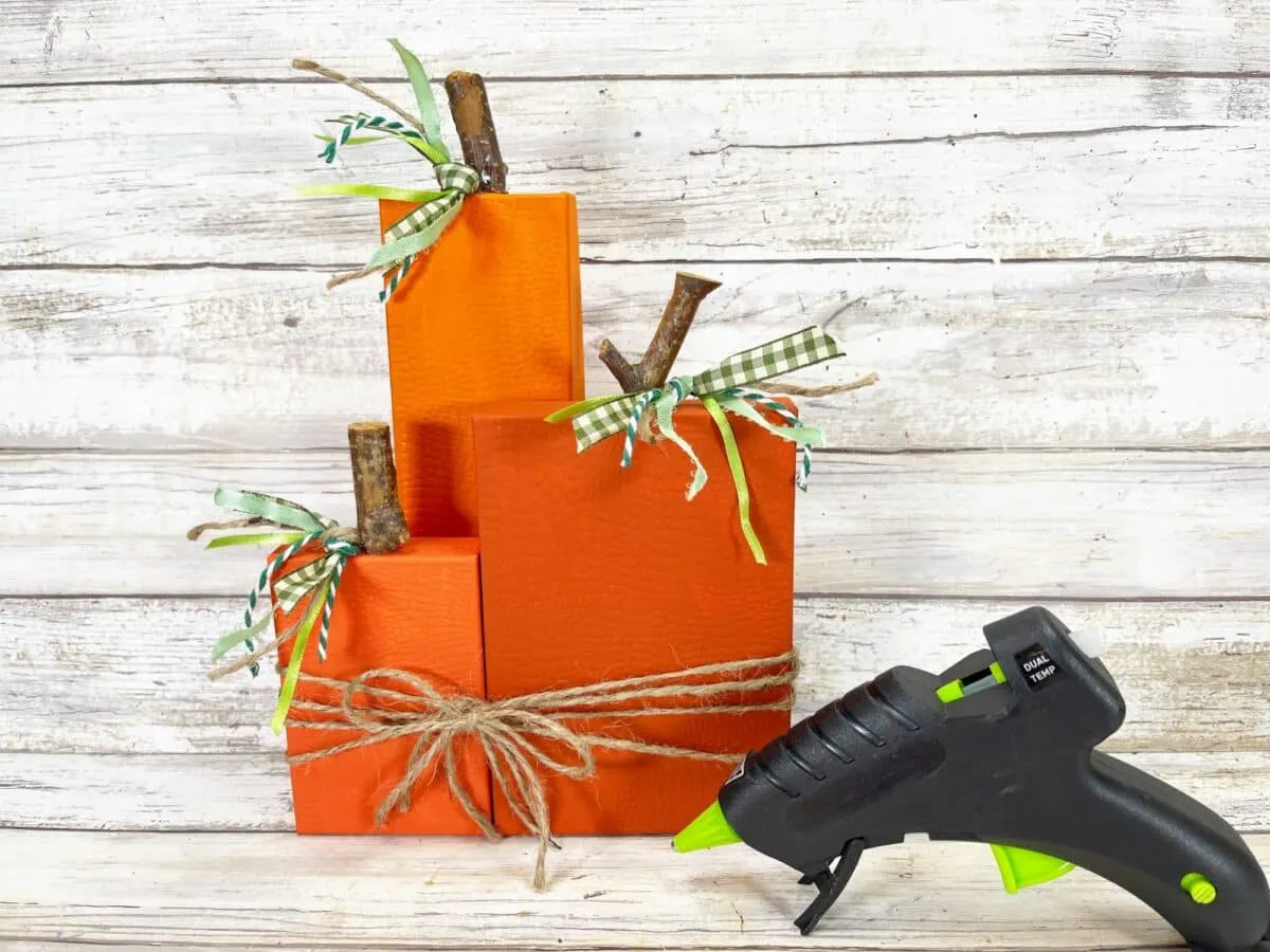 A box of pumpkins with a glue gun next to it.