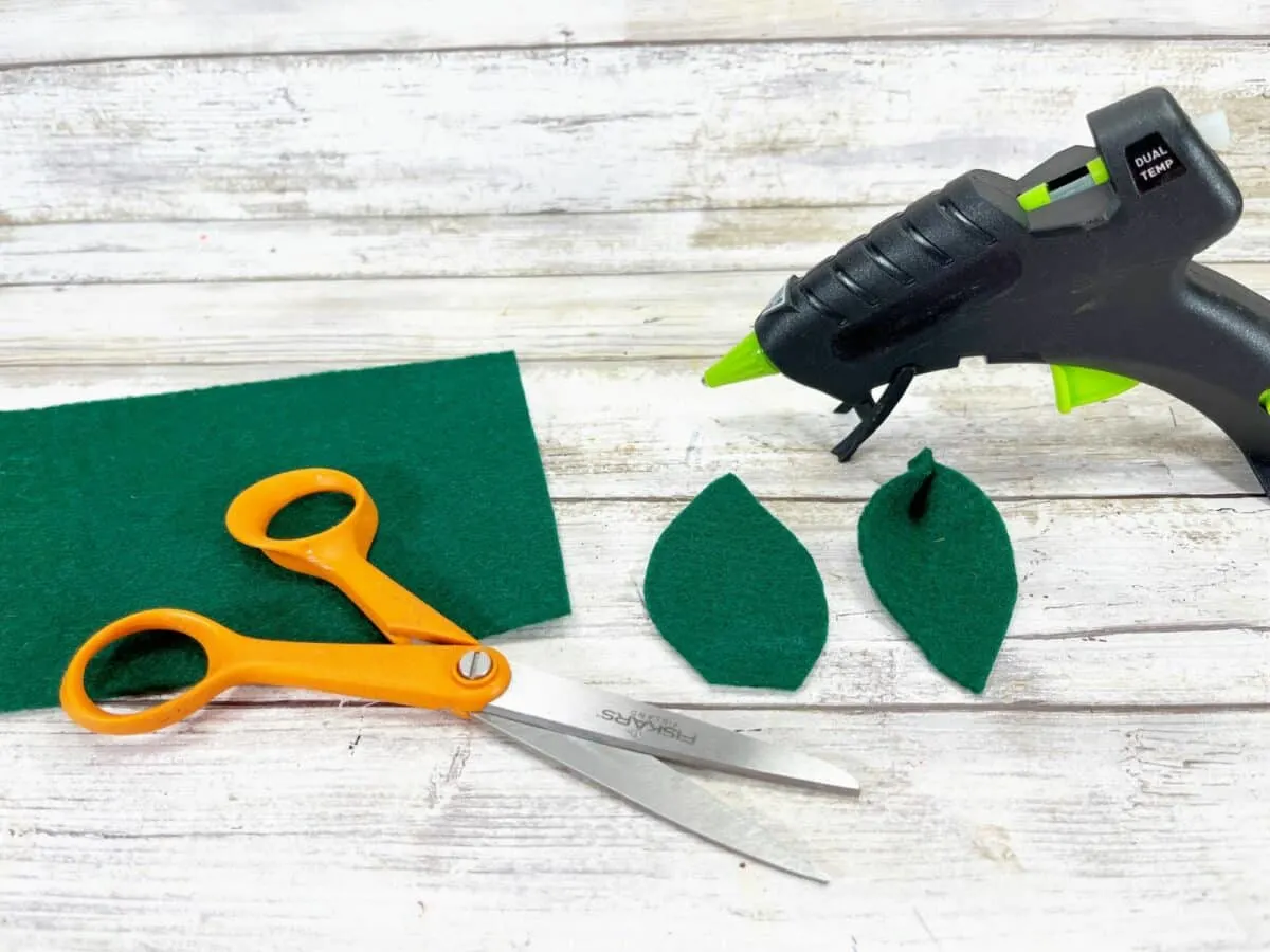 Scissors and glue gun next to felt leaves.