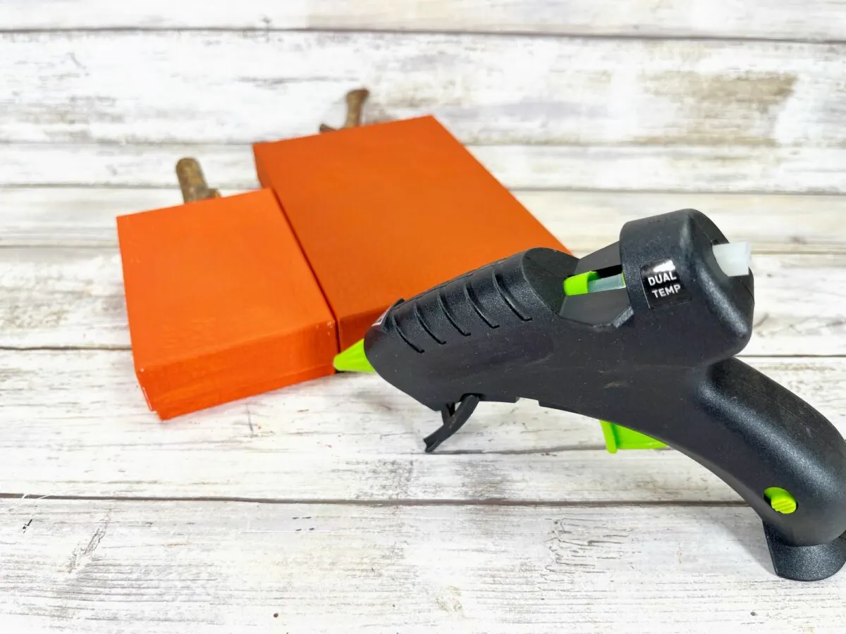 A black and orange glue gun on a wooden surface.
