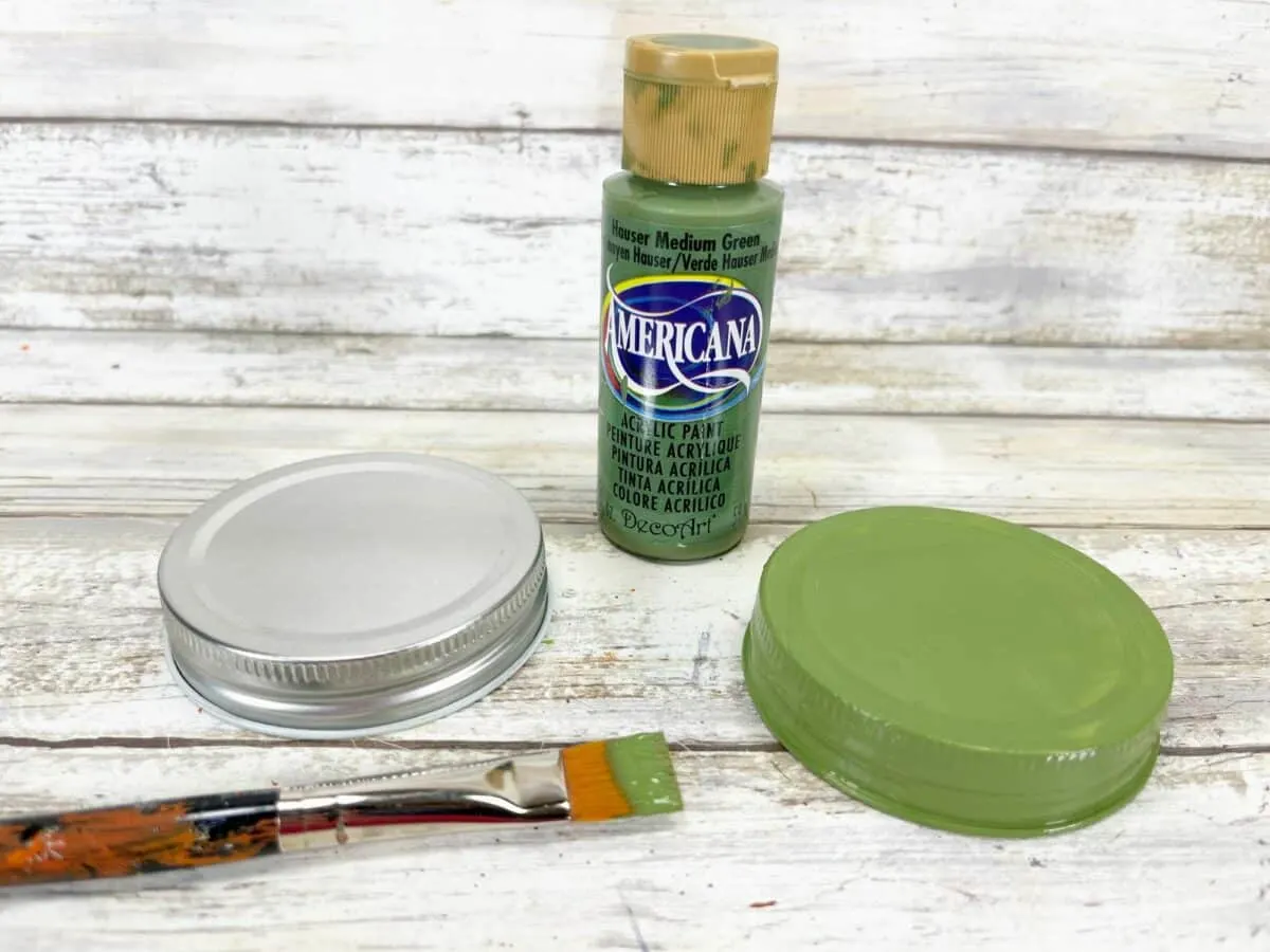A bottle of green paint and a brush next to it.